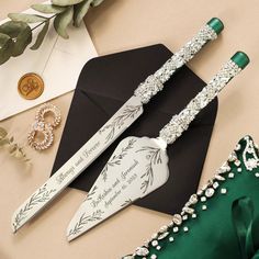 two green and white wedding knifes sitting on top of a table next to a black envelope