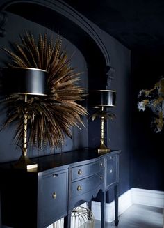 a table with two lamps on top of it next to a dresser and mirror in a room