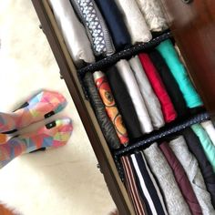 a person standing in front of an open drawer filled with folded clothes and socks on the floor