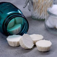 three white cupcakes sitting on top of a counter next to some glass jars