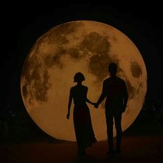 two people holding hands in front of the moon