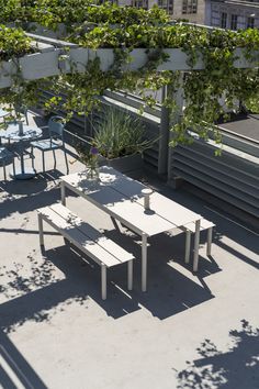 an outdoor table and benches with plants on top