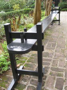 two black benches sitting next to each other on a brick walkway