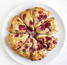 a white plate topped with scones covered in raspberry filling on top of a table