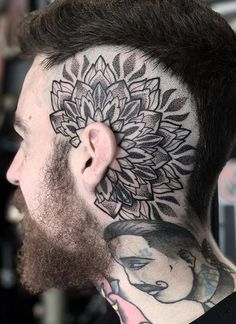 a man with a tattoo on his head and neck is looking at the back of his head