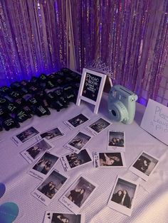 a table topped with pictures and other items next to a purple wall covered in sequins