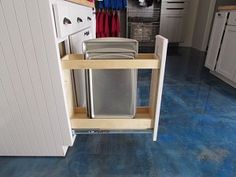 a kitchen with blue flooring and cabinets in the background, there is a trash can on the bottom shelf