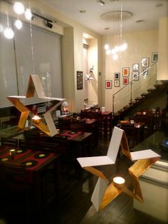 an empty restaurant with wooden tables and star decorations hanging from the ceiling in front of windows