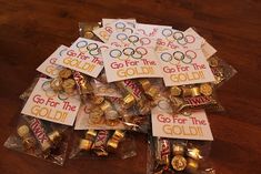 the olympic badges are in plastic bags with gold foil around them on a wooden table