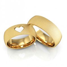 two gold wedding rings with heart cut out in the middle, on a white background