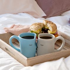 two cups of coffee and a bagel on a tray