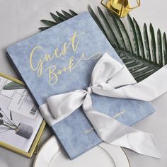 a blue guest book with a white bow on the front and gold lettering that reads guest book