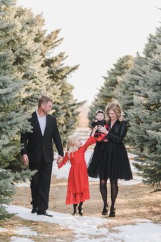 a family holding hands and walking through the snow in their christmas tree farm photo shoot