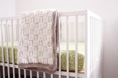 a crocheted blanket hanging from the side of a white crib