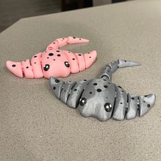 two plastic animals are sitting on the counter top, one pink and one gray with black dots