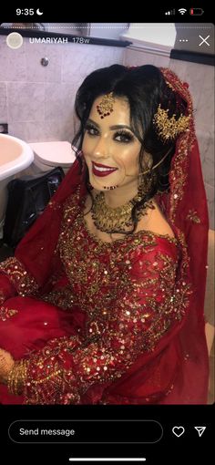 a woman in red and gold makeup is sitting on the floor next to a sink