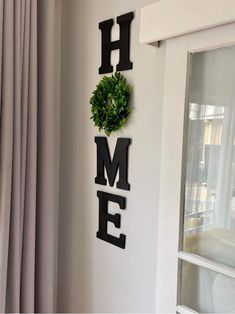 the word home is hanging on the wall next to a wreath and window sill