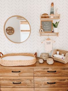 a wooden dresser topped with a baby's crib next to a wall mounted mirror