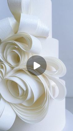 a close up of a white cake with paper flowers on it's top tier