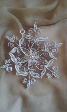 a white paper snowflake sitting on top of a brown cloth covered tablecloth