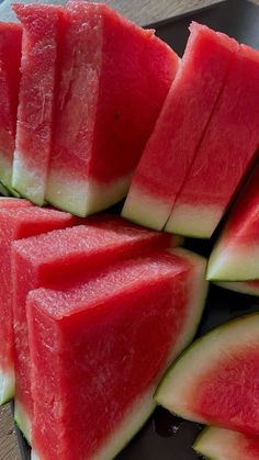 slices of watermelon are arranged on a black plate with chocolate sauce in the middle