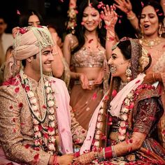 the bride and grooms are surrounded by petals as they sit on the floor in front of their guests