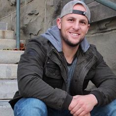 a young man sitting on the steps with his hands crossed and smiling at the camera