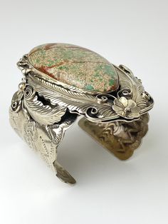 "Vintage Artisan Natural Sea Sediment Jasper Cuff Bracelet - Beautifully made by Navajo artist Percy Spencer - piece is signed - Substantial heavy rigid cuff - Navajo or coin silver, non-magnetic - Huge stone surrounded by very intricate silver work with feathers, flowers, swirls and stamp work on the arm cuff - The jasper stone is natural with lots of green, dark brown matrix and a tan colored background. Almost perfect teardrop shape. - Face of cuff measures 3.5\" x 2.5\" - Width of arm band 2 Artisan Adjustable Cuff Bracelet With Intricate Design, Artisan Cuff Bracelet With Intricate Adjustable Design, Bohemian One-of-a-kind Cuff Bracelet, Southwestern Cuff Collectible Jewelry, Southwestern Style Collectible Cuff Jewelry, Artisan Etched Cuff Bracelet, Vintage Hand-tooled Cuff Jewelry, Bohemian Patina Cuff Bracelet, Unique Collectible Cuff Jewelry