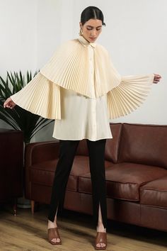 The blouse is impressive with a pleated cape and sleeves design symbolizing the wings that bring freedom in fashion. Special silk material is used for creating a soft look and bringing a relaxed feeling to the wearer. Note:*Processing time takes 7-10 working days (including 3-5 working days for manufacturing and NOT including shipping time)**Backorder Definition- The product is low in stock and in case the customer purchased successfully after out of stock, the order will need time to restock.- Harsh Winter Outfits, Oversized Elegant Cape For Spring, Elegant Cape Top For Spring, Chic Capelet With Cape Sleeves For Work, Elegant Spring Cape Top, Chic Long Sleeve Spring Cape, Chic Long Sleeve Pleated Blouse, Luxury Blouse With Pleated Lantern Sleeves, Luxury Feminine Top With Pleated Sleeves