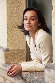 a woman sitting on the ledge of a building with her arms crossed and looking off into the distance