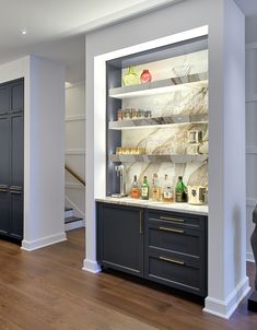 an empty kitchen with marble counter tops and black cabinetry, along with wooden flooring