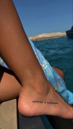 a woman's foot with the words nothing is permanent written on it and an ocean background