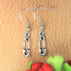 two pairs of silver earrings sitting on top of a wooden table next to red berries