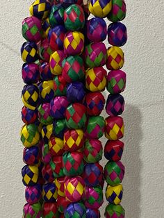 a bunch of colorful balls hanging from a hook on the wall in front of a white wall