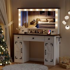 a christmas tree is in front of a vanity with lights on it and a mirror