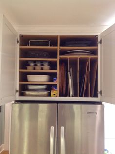 an open cabinet in the middle of a kitchen with dishes and utensils on it