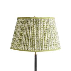 a lamp with a green and white shade on it's side, against a white background