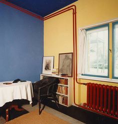 a room with a table, chair and radiator next to a window in it