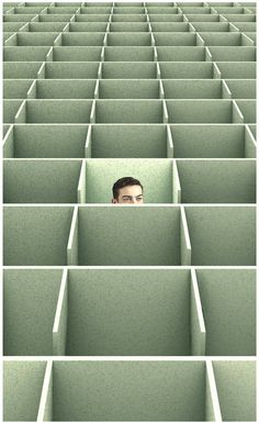 a man's face is peeking out from the middle of a row of cubicles