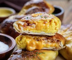 three breakfast burritos stacked on top of each other next to dipping sauces