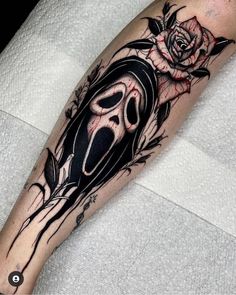 a black and white tattoo with a rose on the arm, in front of a person's leg