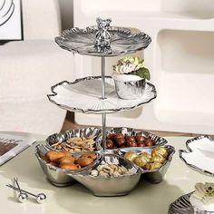 three tiered trays filled with food on top of a table next to plates and utensils