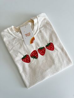 a white t - shirt with three strawberries on it