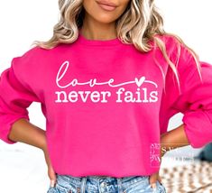 a woman wearing a pink sweatshirt with the words love never falls printed on her chest