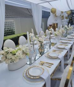 a long table with white and gold place settings