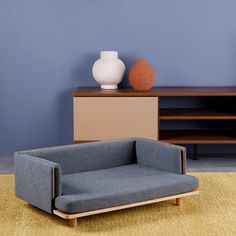 a blue couch sitting on top of a rug next to a white vase and shelf