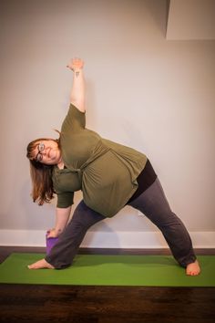 a woman is doing yoga in front of a wall with her hands up to the side