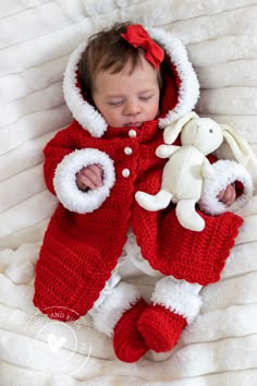 a baby is wearing a red and white outfit with a stuffed animal in it's lap