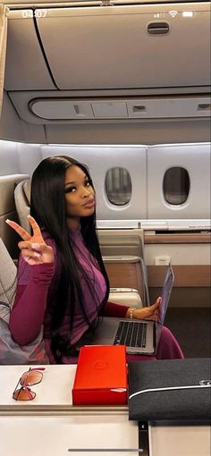 a woman sitting on an airplane with her laptop in front of her and pointing to the side