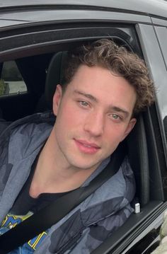 a young man sitting in the back seat of a car